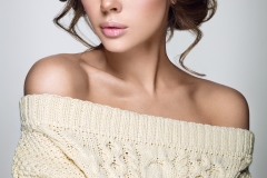 Beautiful woman portrait. Young lady posing in warm sweater. Nice makeup and hairstyle. Studio photo shoot.
